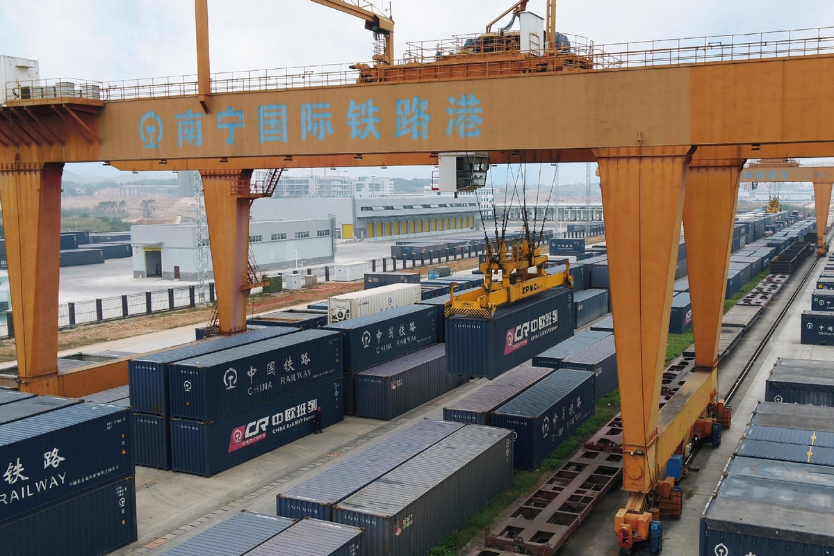 A crane loads containers onto a freight train before its departure from Nanning, Guangxi Zhuang autonomous region, on Dec 31, 2021. [Photo/Xinhua]