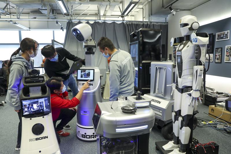 Young engineers discuss robots they produce at a new company in the city. (ZHU HONGBO / FOR CHINA DAILY)