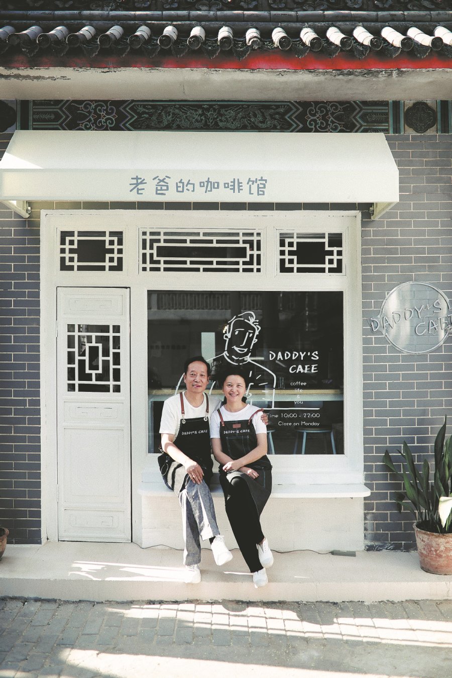 Shen and his wife pose in front of the cafe he owns in Xianyang, Shaanxi province. CHINA DAILY 