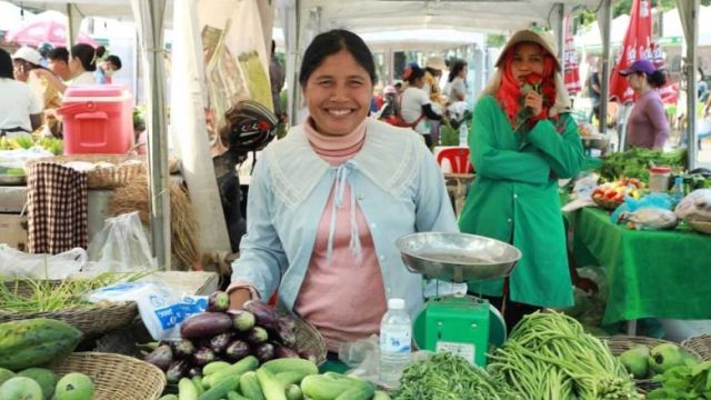 a_woman_smiles_as_she_sells_vegetables_at_a_flourishing_local_market._australian_embassy.jpg