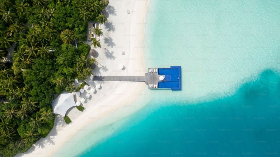 an-aerial-view-of-a-beach-with-a-dock-and-palm-trees-Xppu_HZiG-E.jpg