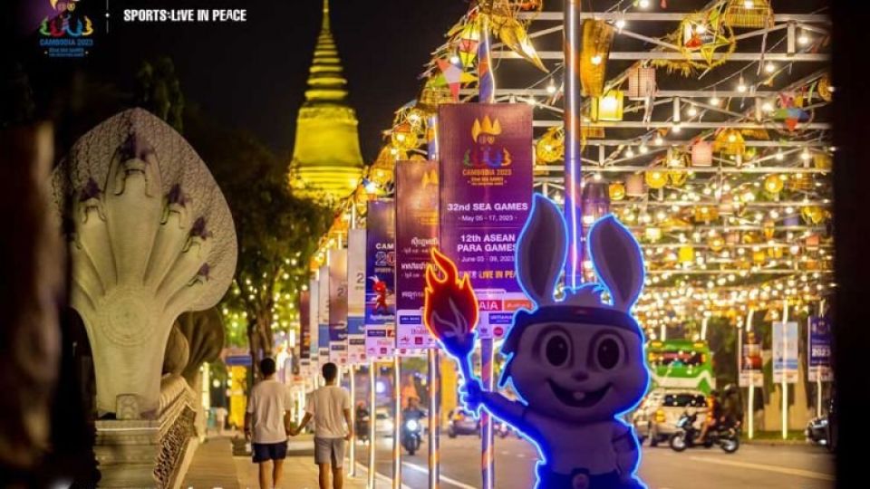 two_men_hold_hands_as_they_walk_towards_wat_phnom_passing_decorations_for_the_32nd_sea_games_and_12th_asean_para_games._cambodia_2023.jpg